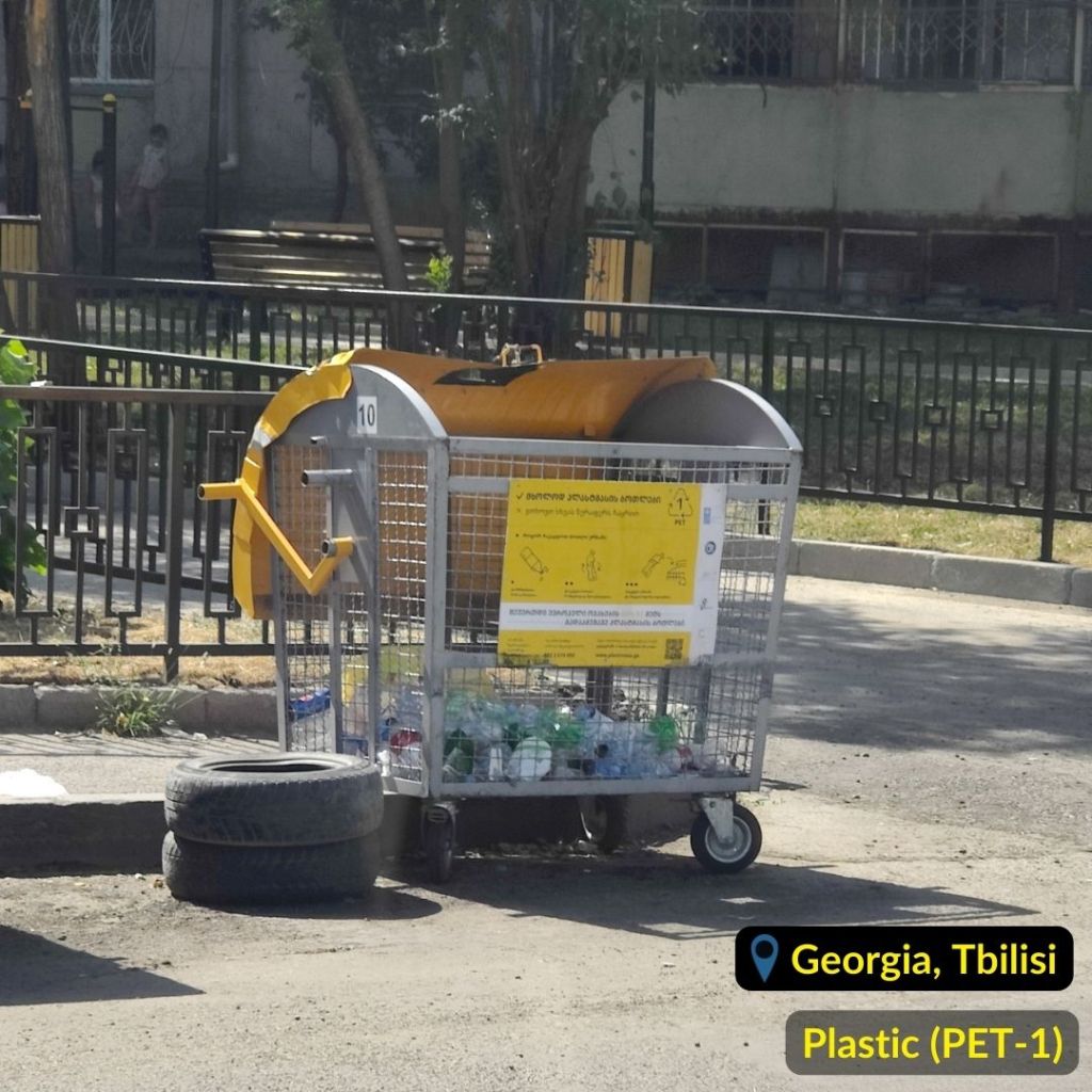 Yellow and metallic PET-1 plastic bottles recycling bin in Tbilisi Georgia. 2 tires are laying nearby